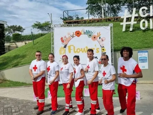Voluntários de camiseta branca e calça vermelha em um evento ao ar livre